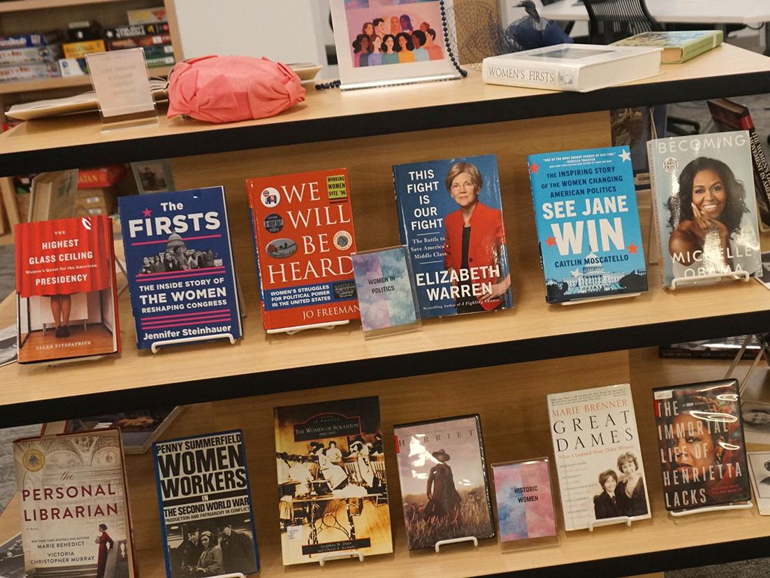 a multi-tiered shelving display with books about and by women throughout history
