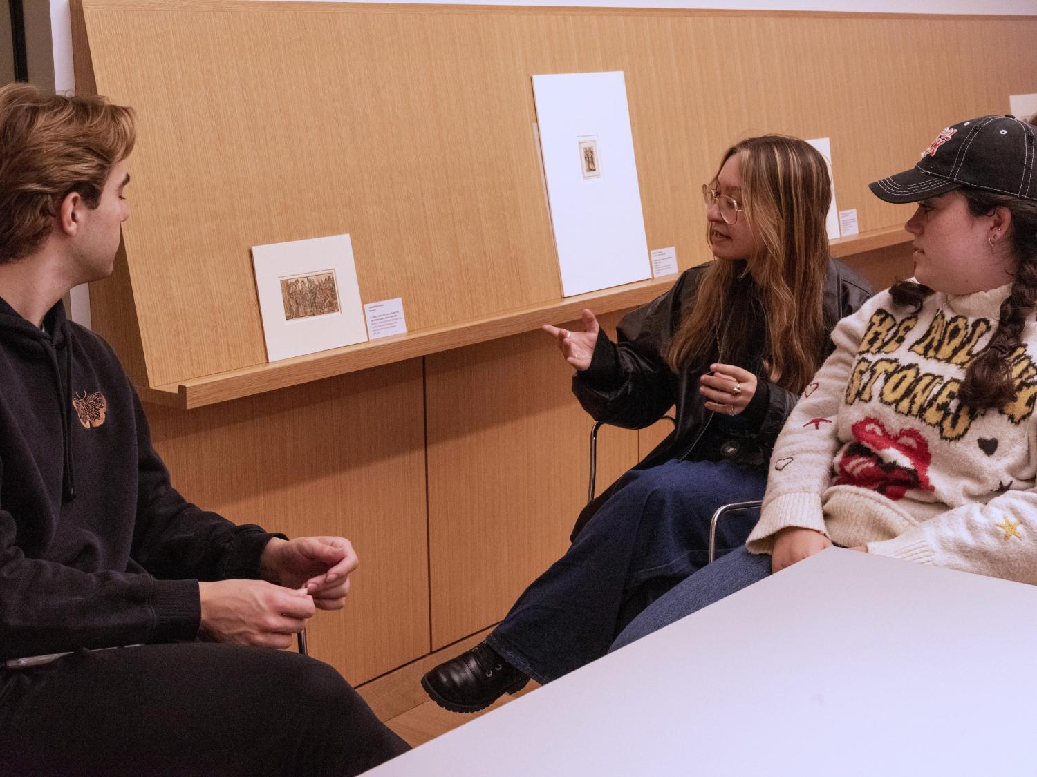 Three students discuss a small piece of art