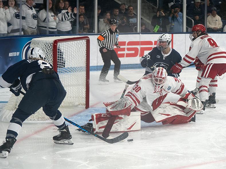 Hockey player shoot puck at goal with goalie in front