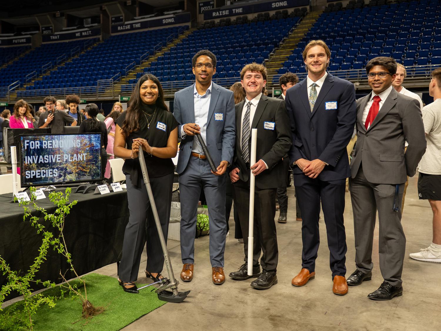 Engineering students pose next to their capstone design project for the removal of invasive plant species.