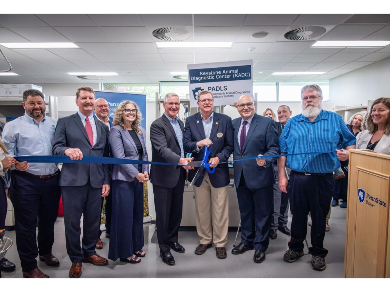 People in a line, cutting a blue ribbon
