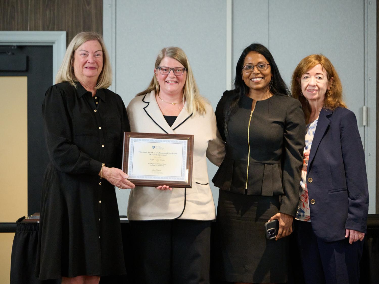 Four women standing together, holding a framed certificate