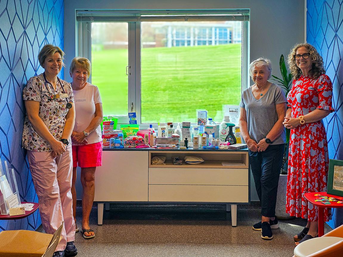 Four women stand hear a table covered in toiletry items