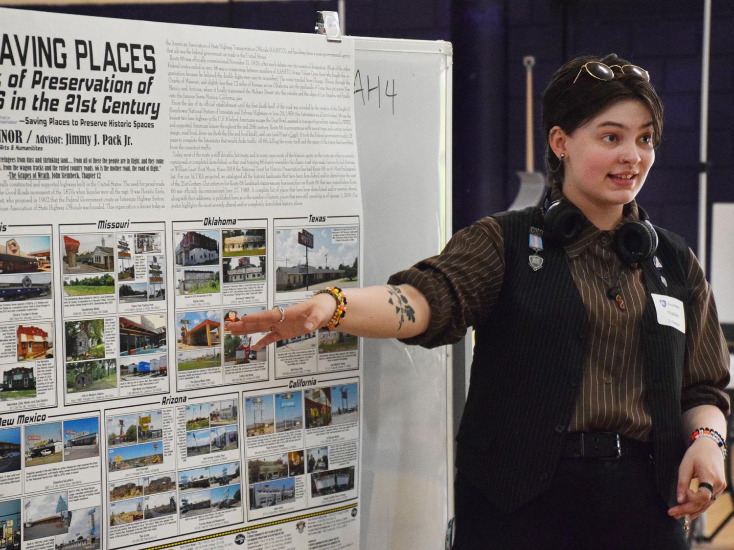 student presenting research and pointing at a poster