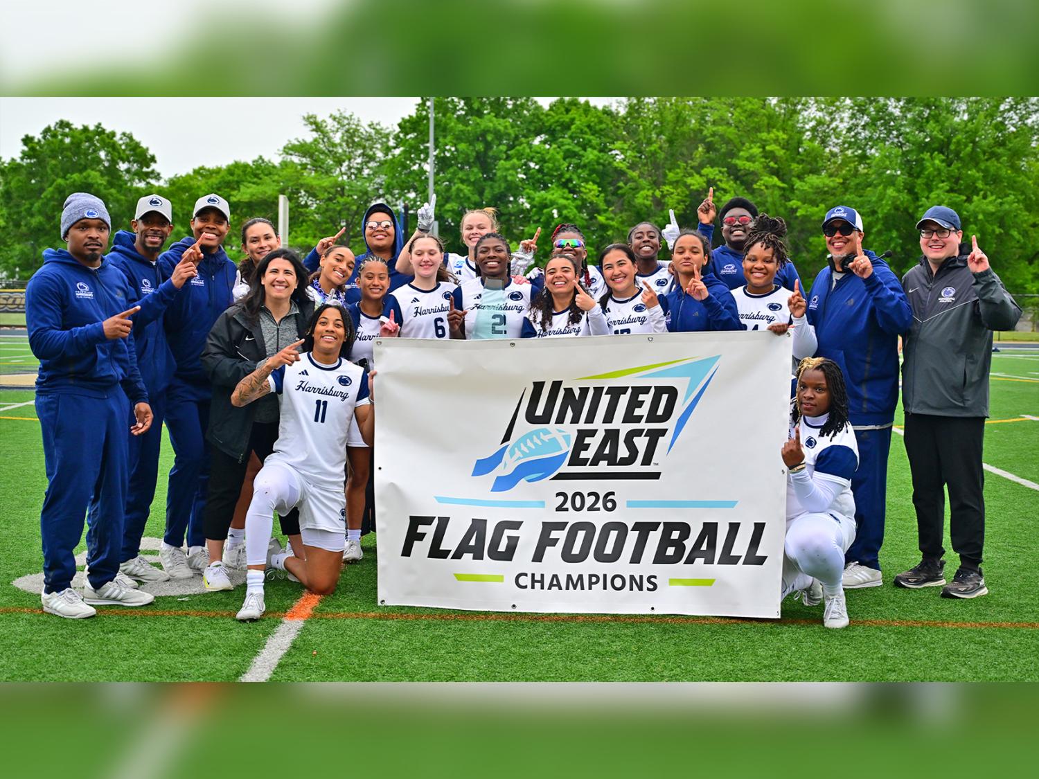 Penn State Harrisburg's women's flag football team members gather around a banner that says United East 2026 Flag Football champions
