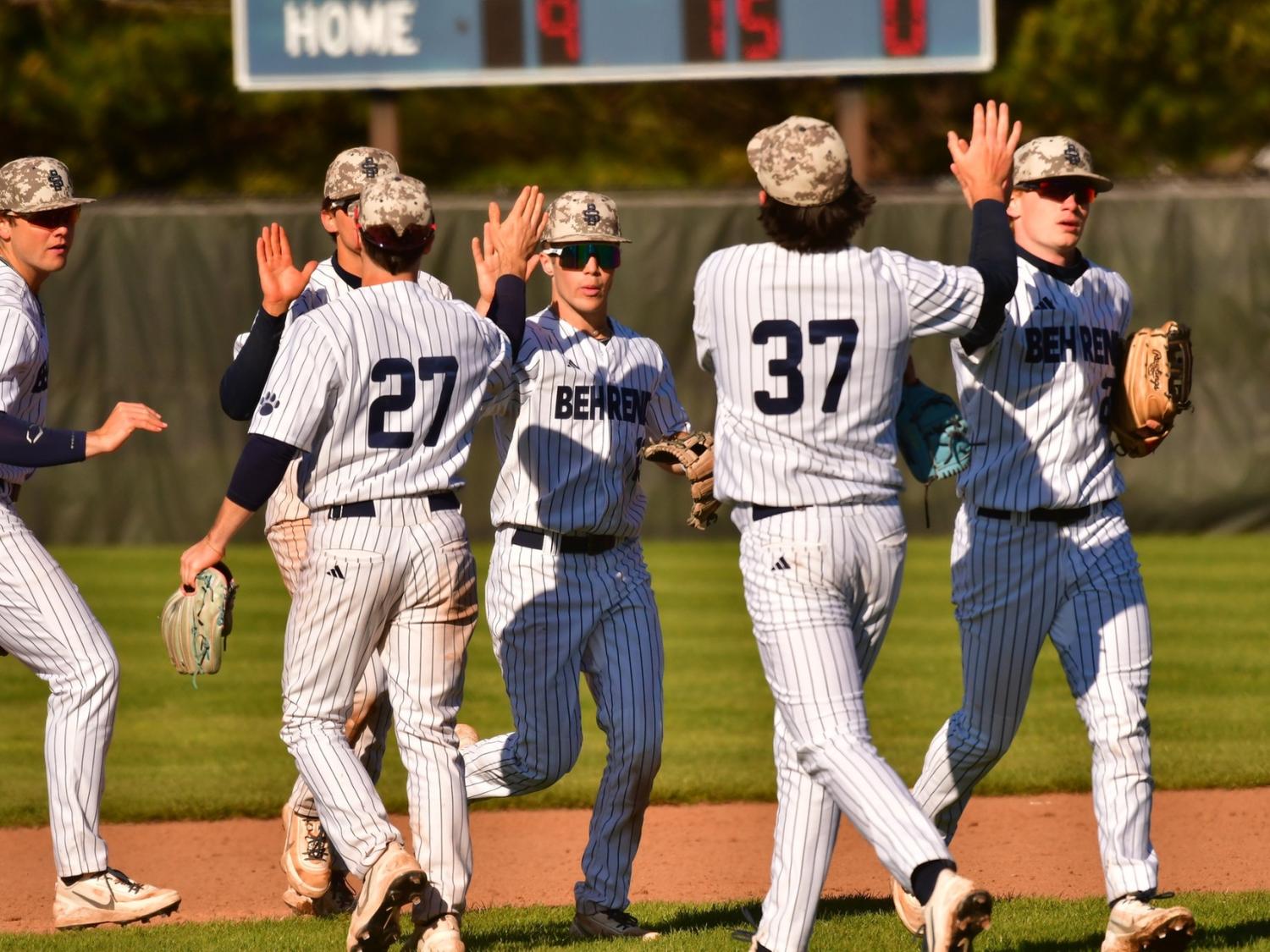 Members of the Penn State Behrend baseball team high-five each other after an inning.