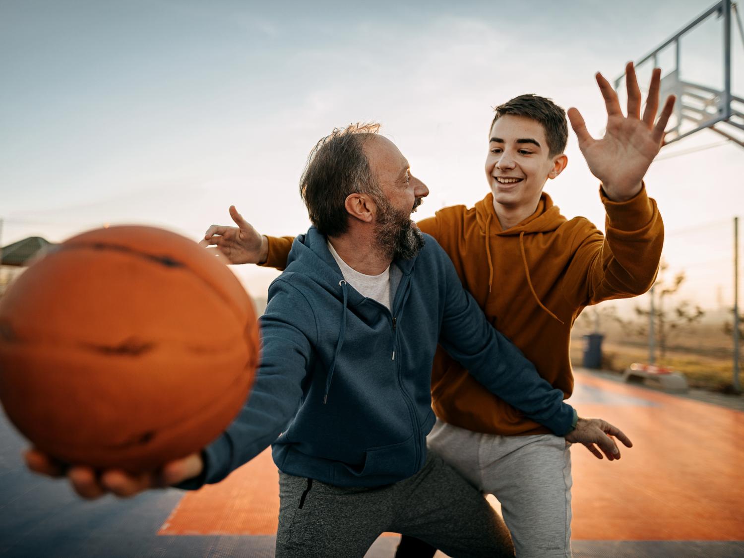 father and teenage son playing basketball