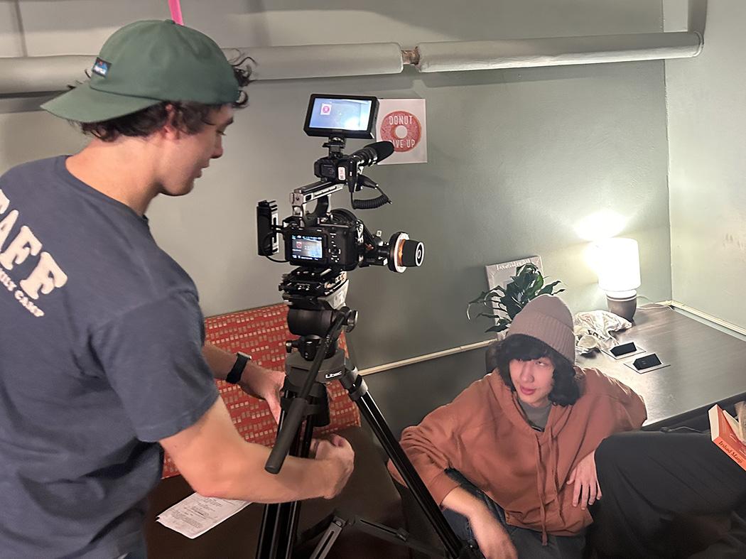 A man in a blue shirt adjusts a camera to shoot a film scene.