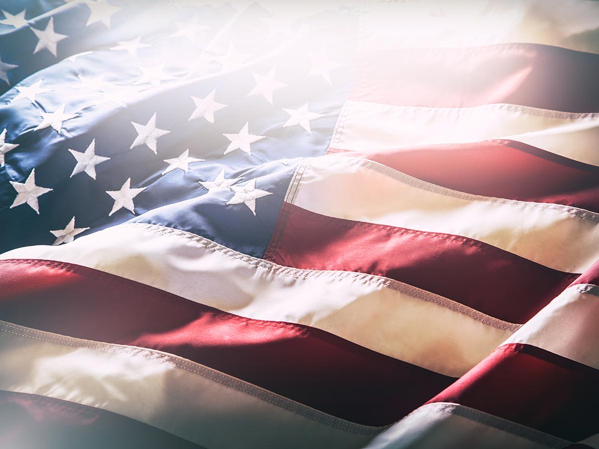 Close-up of the United States flag with stars and stripes softly lit and gently rippling.