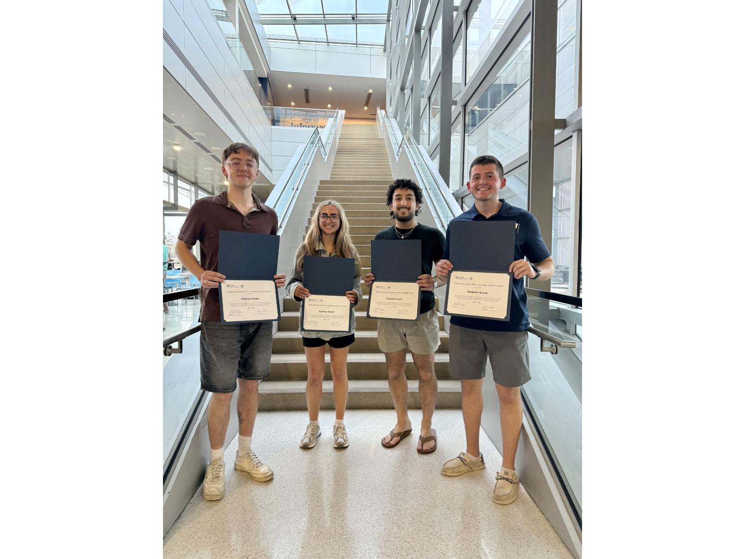 four college students display award certificates 