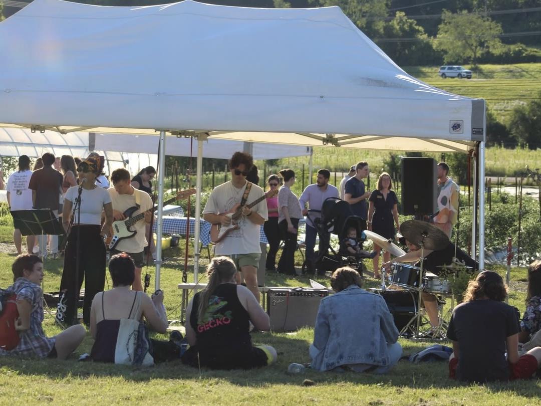 Visitors sit under a tent outside on the Student Farm
