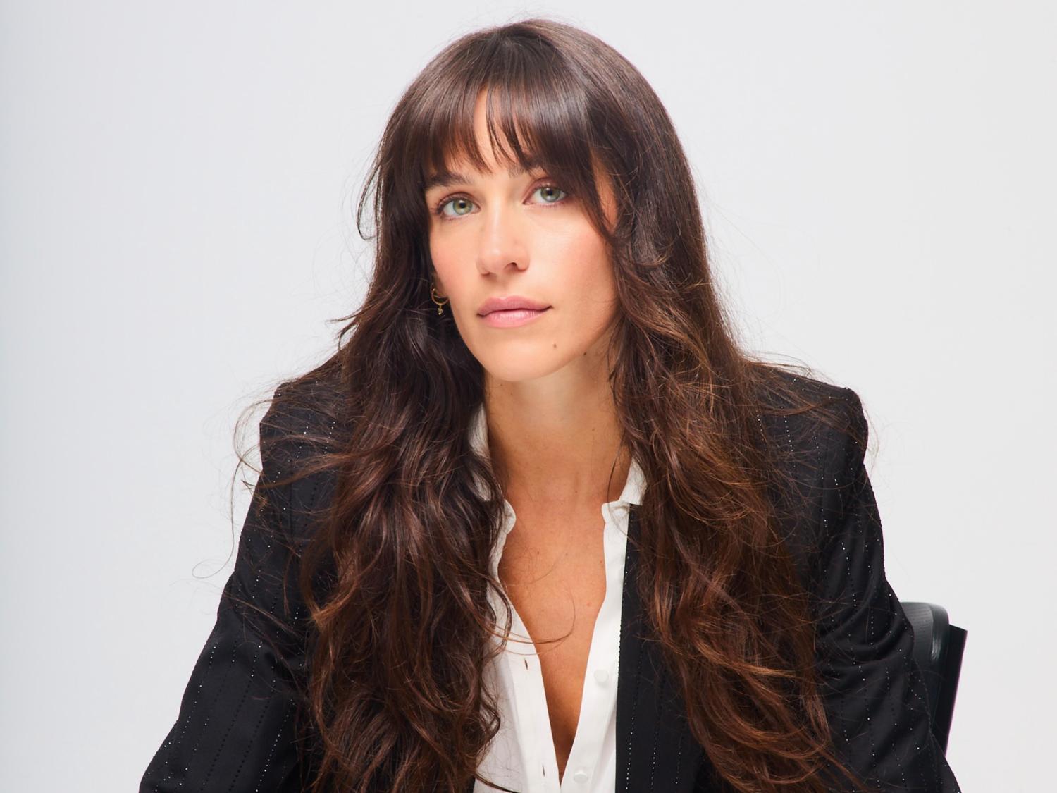 Woman with dark hair, a dark blazer and white shirt