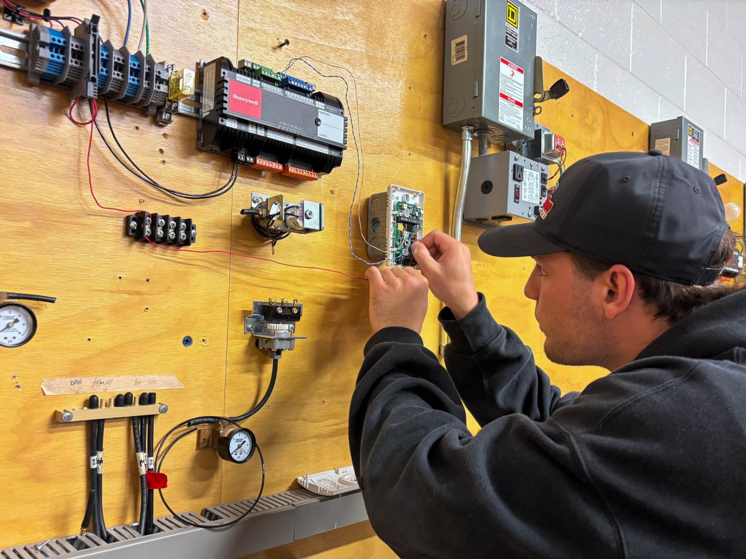 A student works on installing pieces to a vertical board of electronic equipment
