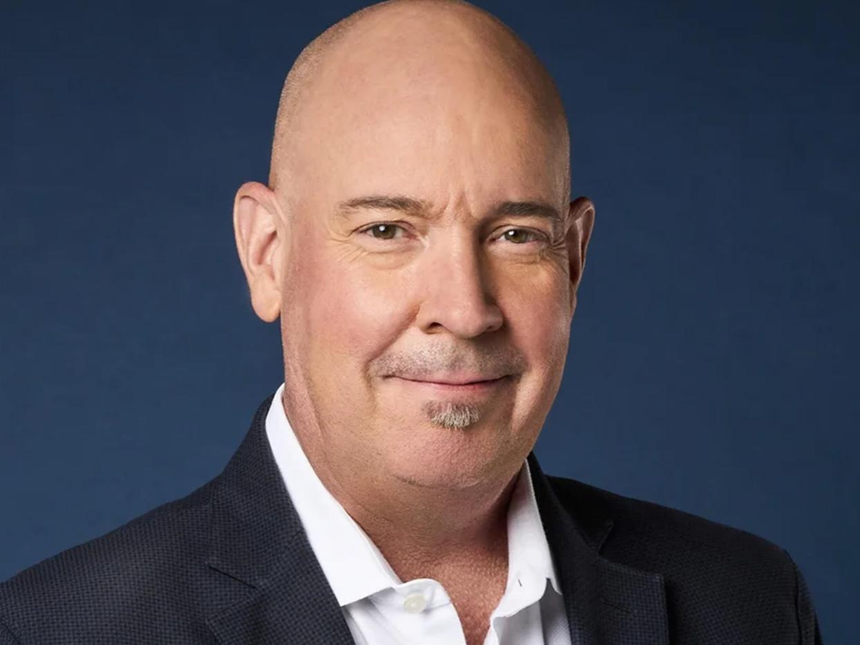 Smiling bald man with a dark coat and white shirt