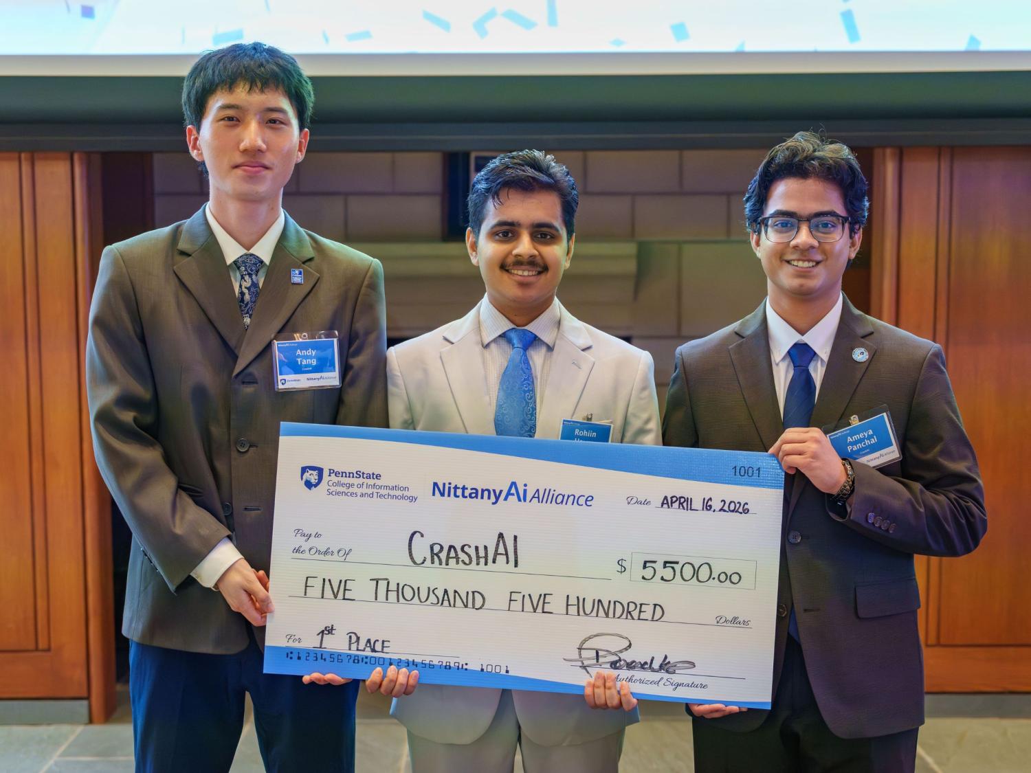 three college students in suits hold giant check