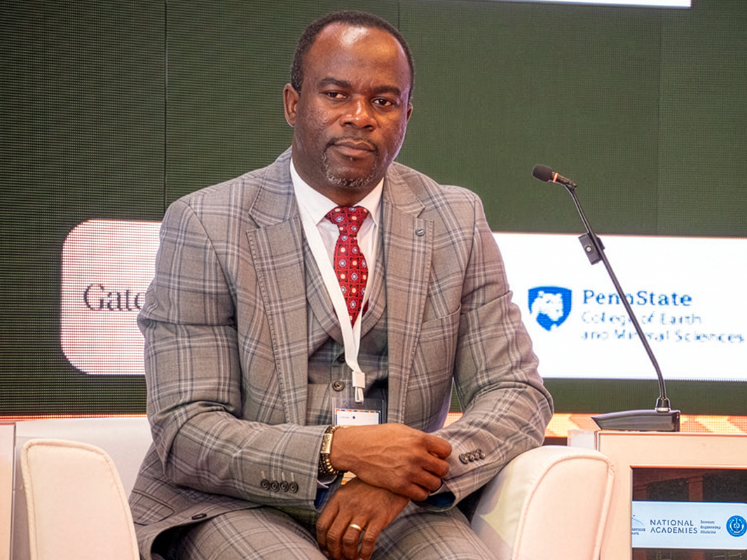 Nelson Dzade sitting on white chair on stage.