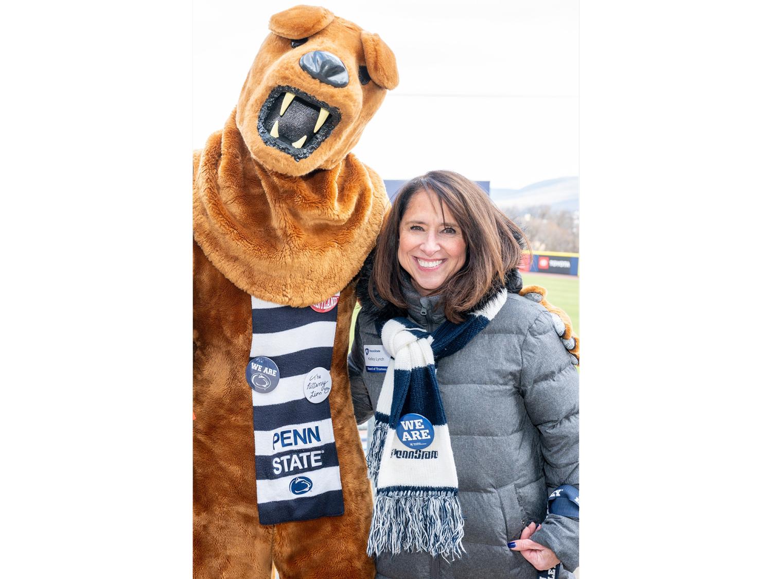 Kelley Lynch and the Nittany Lion mascot wearing Penn State scarves and smiling for the camera