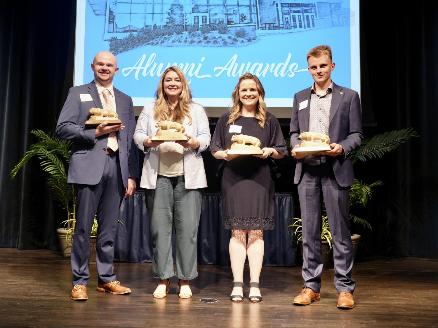 Four people holding small Nittany Lion statues
