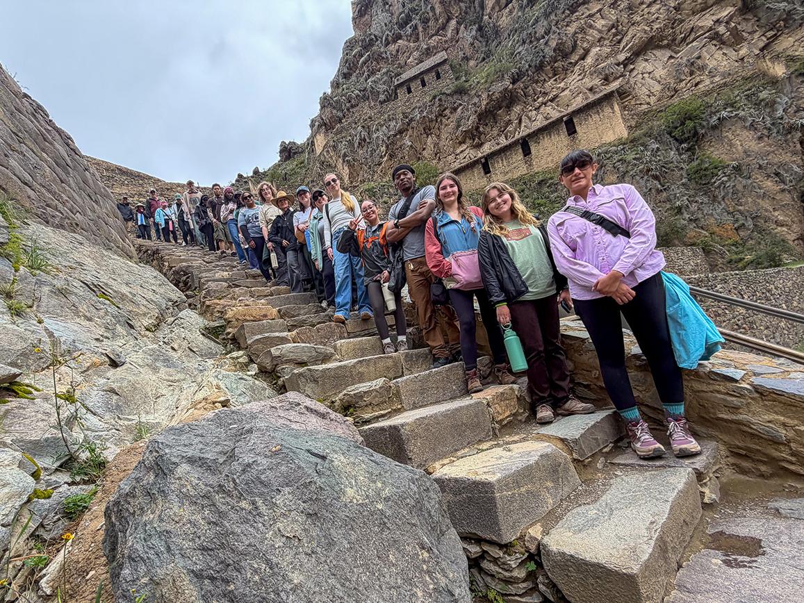 A group of people stand in ascending order on ancient stone steps