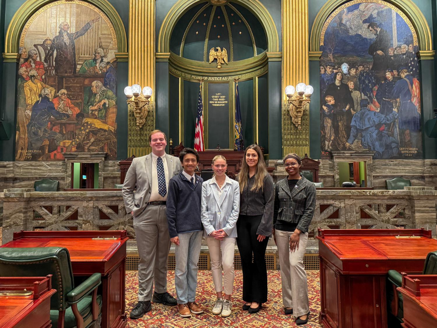 Five students stand in the Senate chamber.