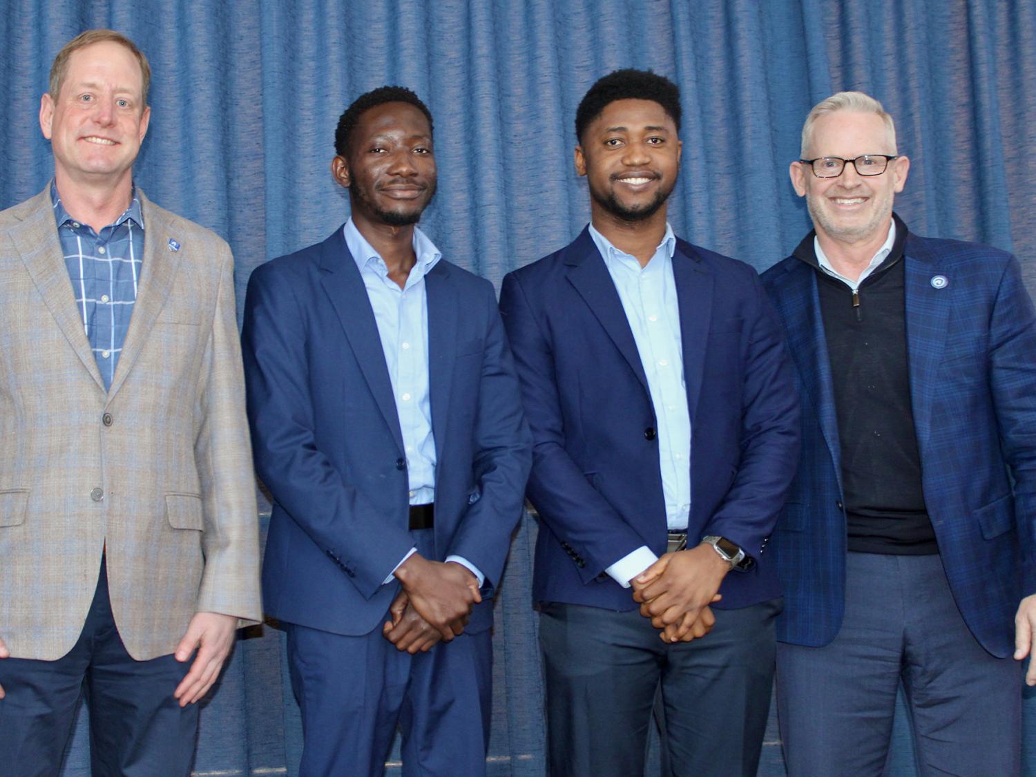 Four men stand shoulder to shoulder
