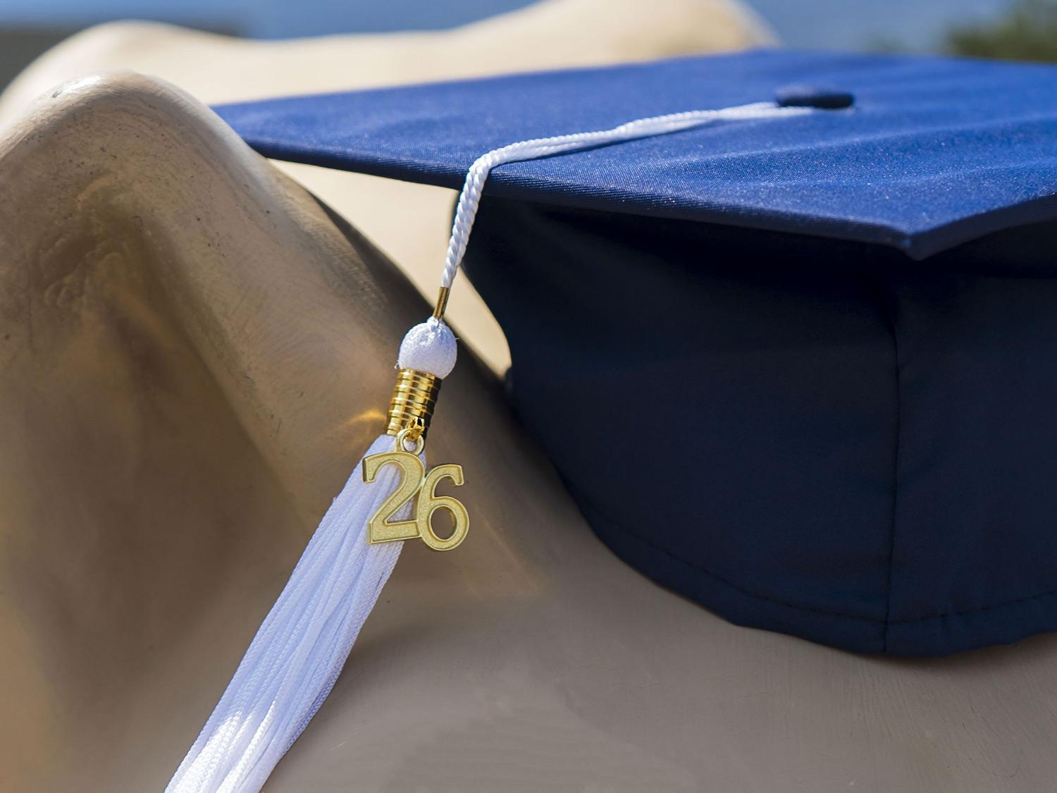 Close-up view of a blue graduation cap with a white tassel and gold “26” charm, resting on Lion Shrine.