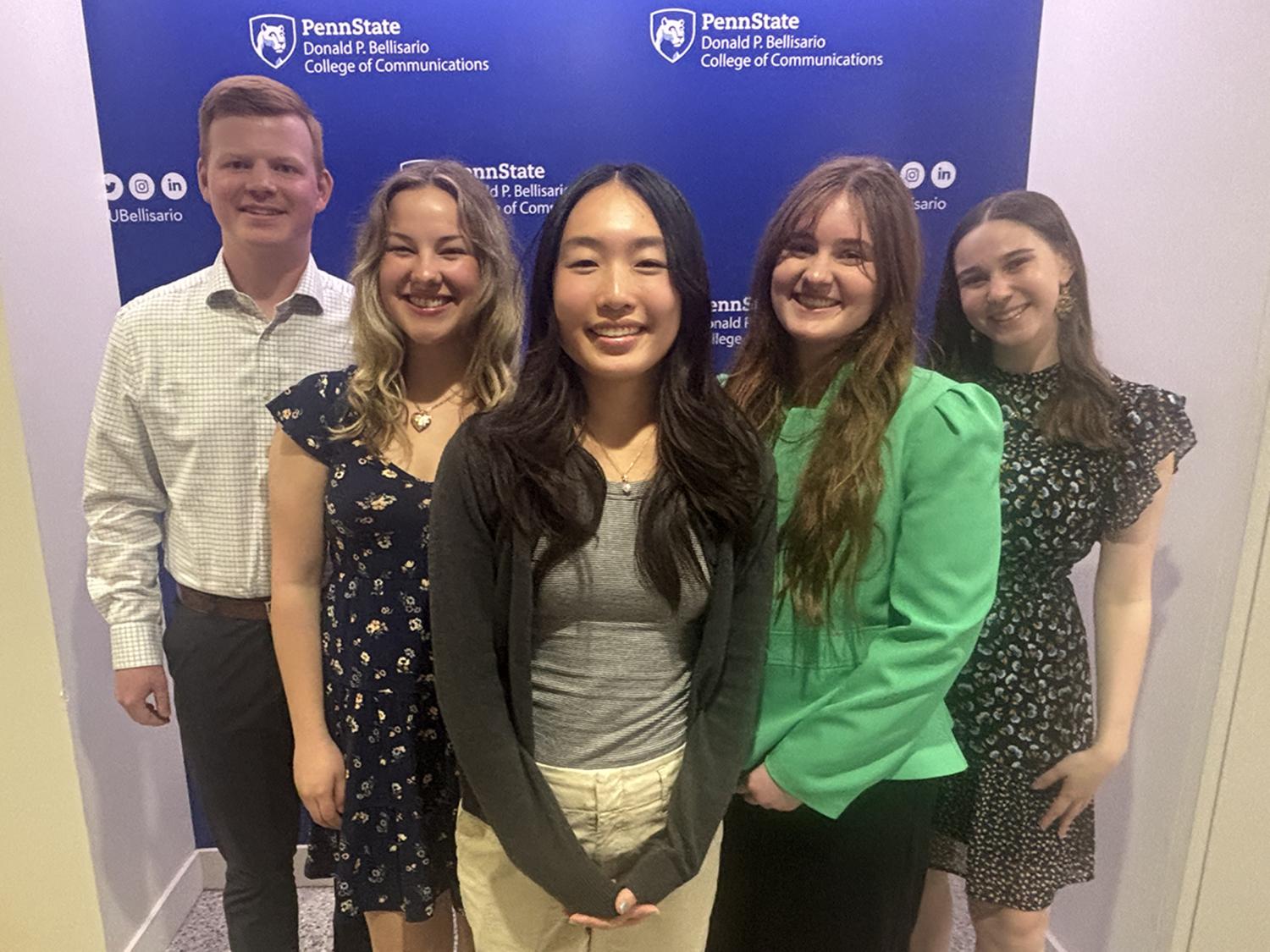 Five smiling students, one man and four women