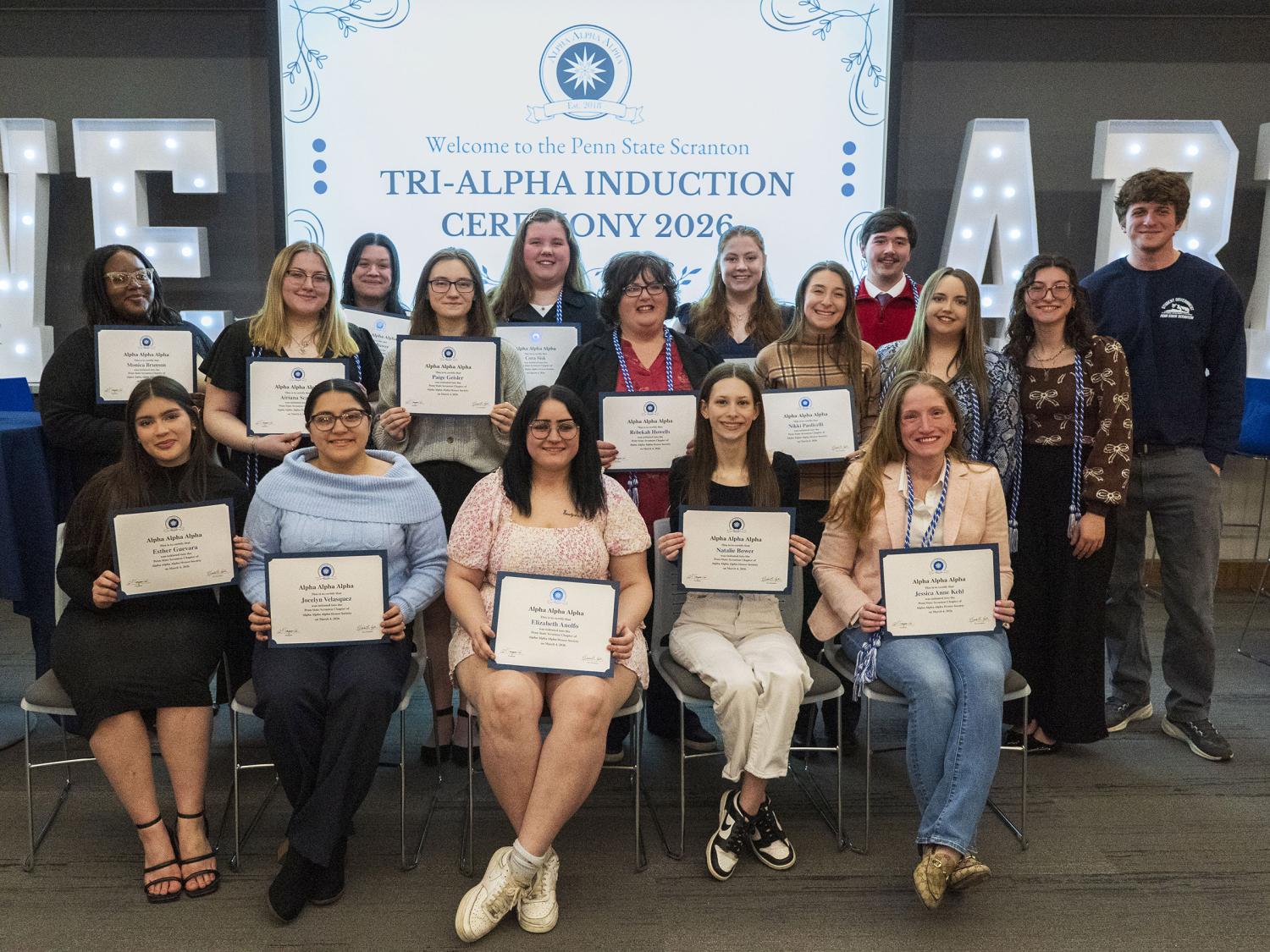 The new inductees into the Tri-Alpha honor society pose for a photo holding their membership certificates in front of them