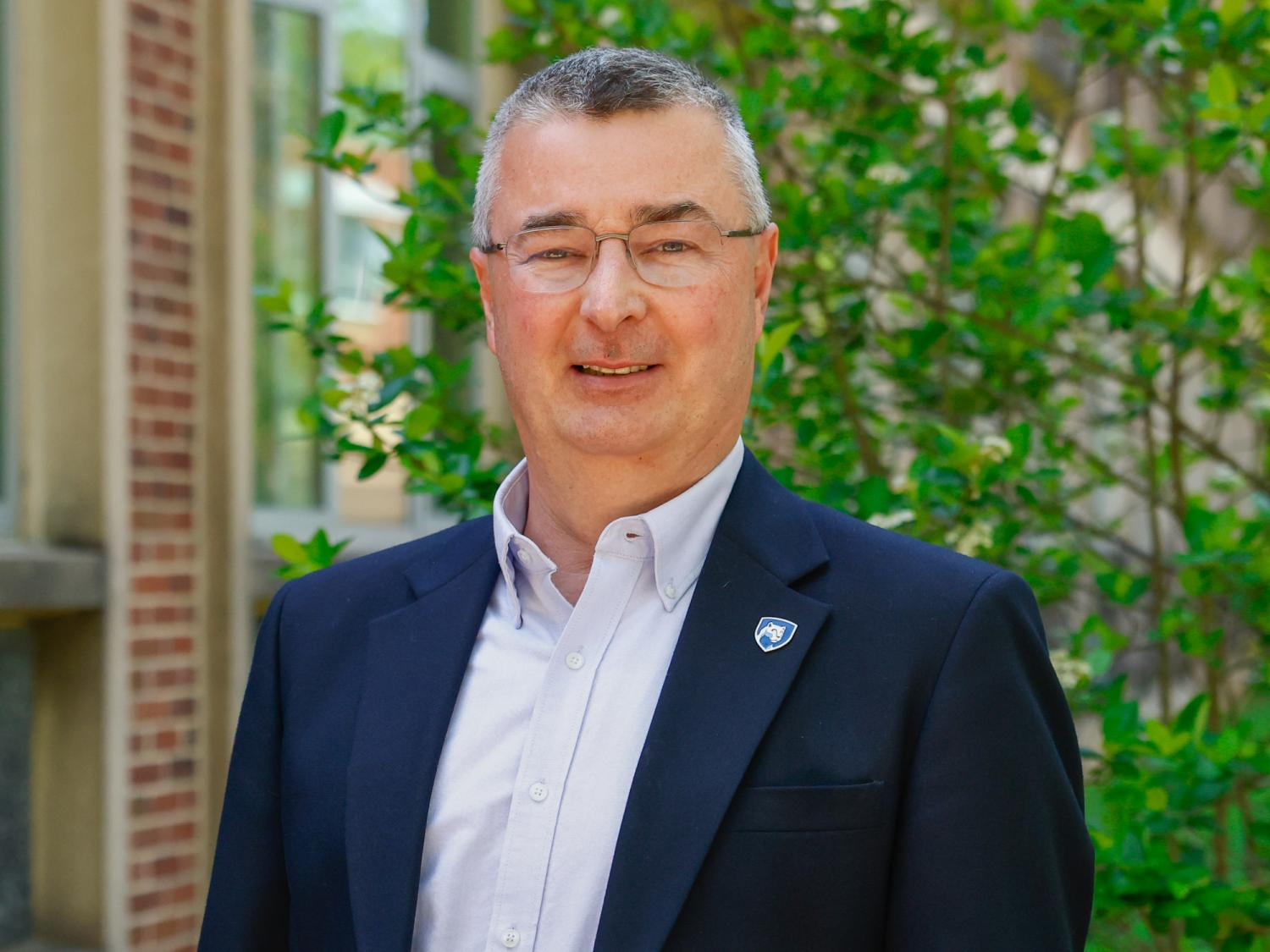 A head shot of a male employee outside a campus building.
