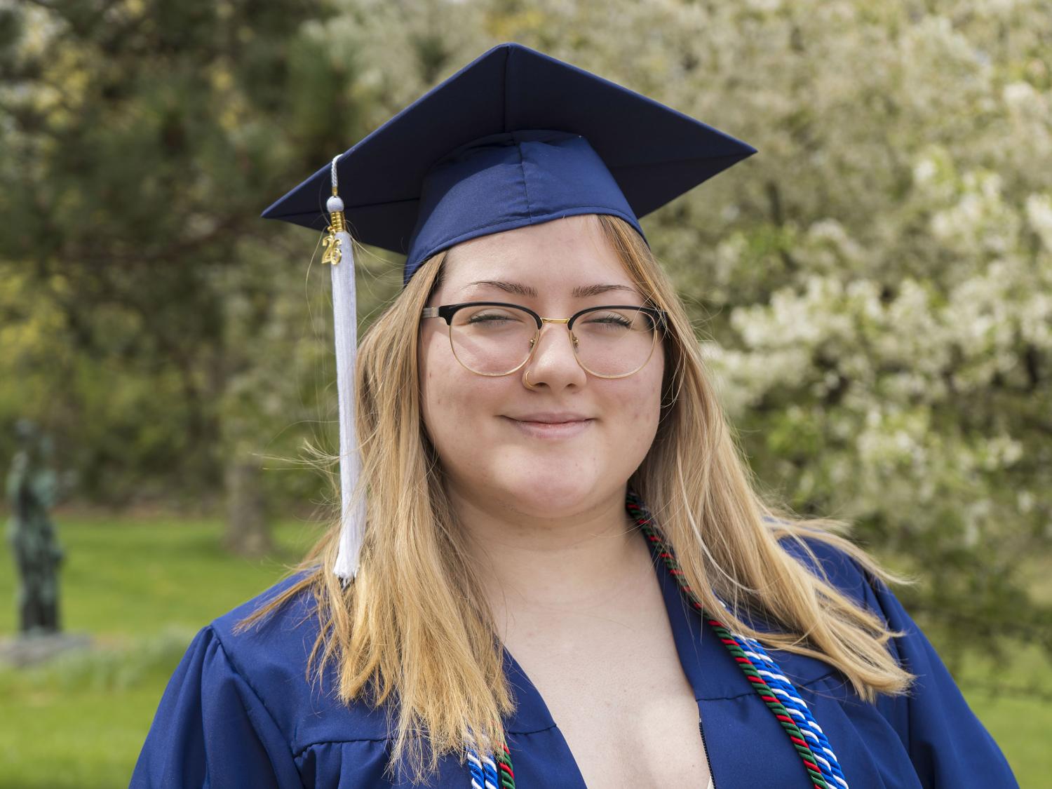 Penn State female graduate smiles for a photo wearing blue commencement reglia. 