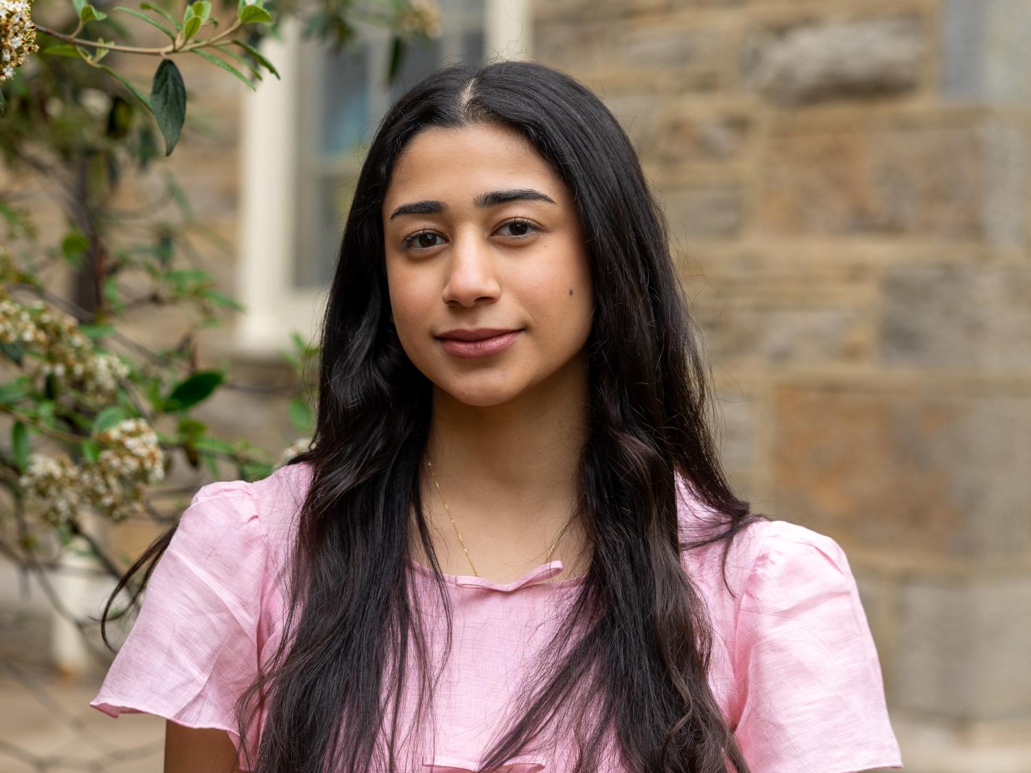Rand Alkhunaizi wears a pink blouse in front of Old Main.