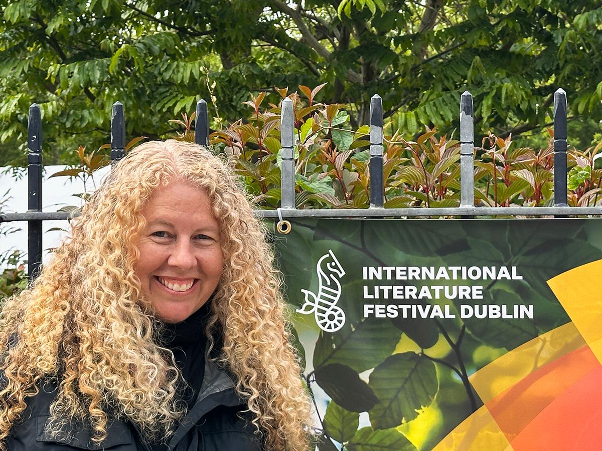Penn State professor Erin Murphy standing beside banner for International Literature Festival Dublin outdoors.
