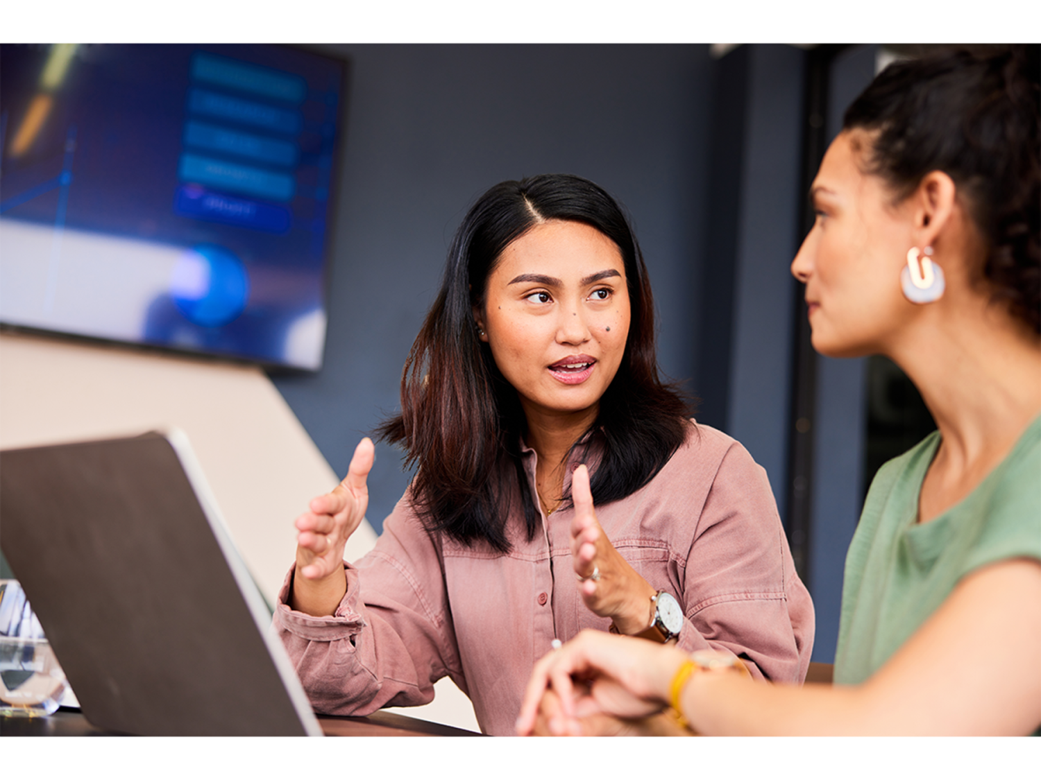 Person with laptop explaining and gesturing to colleague