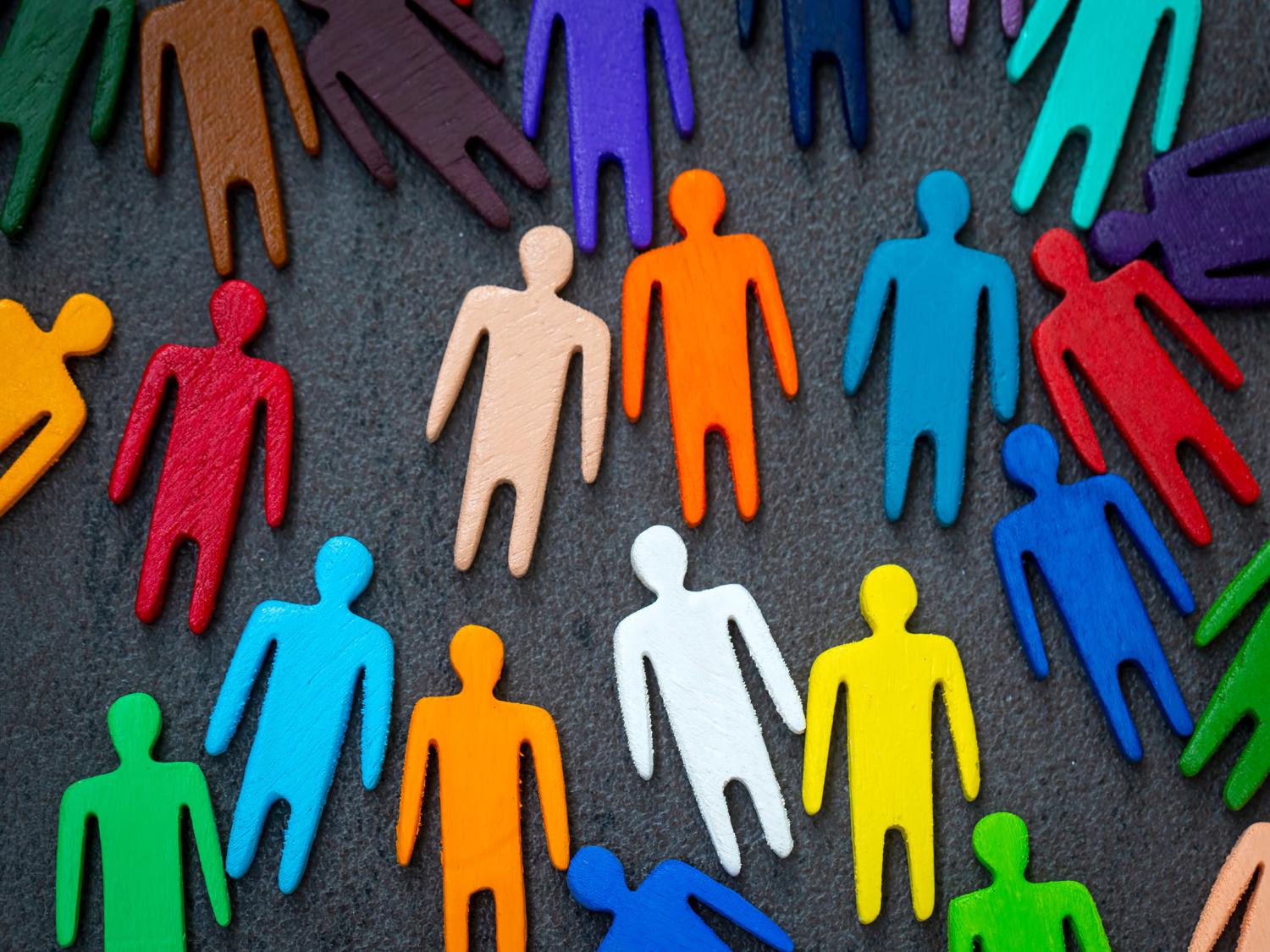 Equality and diversity concept image of multi-colored wooden figurines on a blackboard.