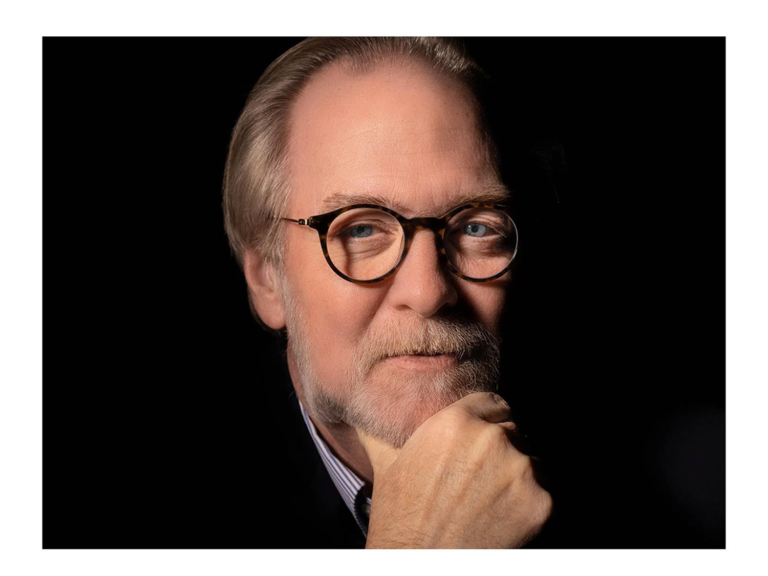 Man wearing glasses with his hand resting on his chin.