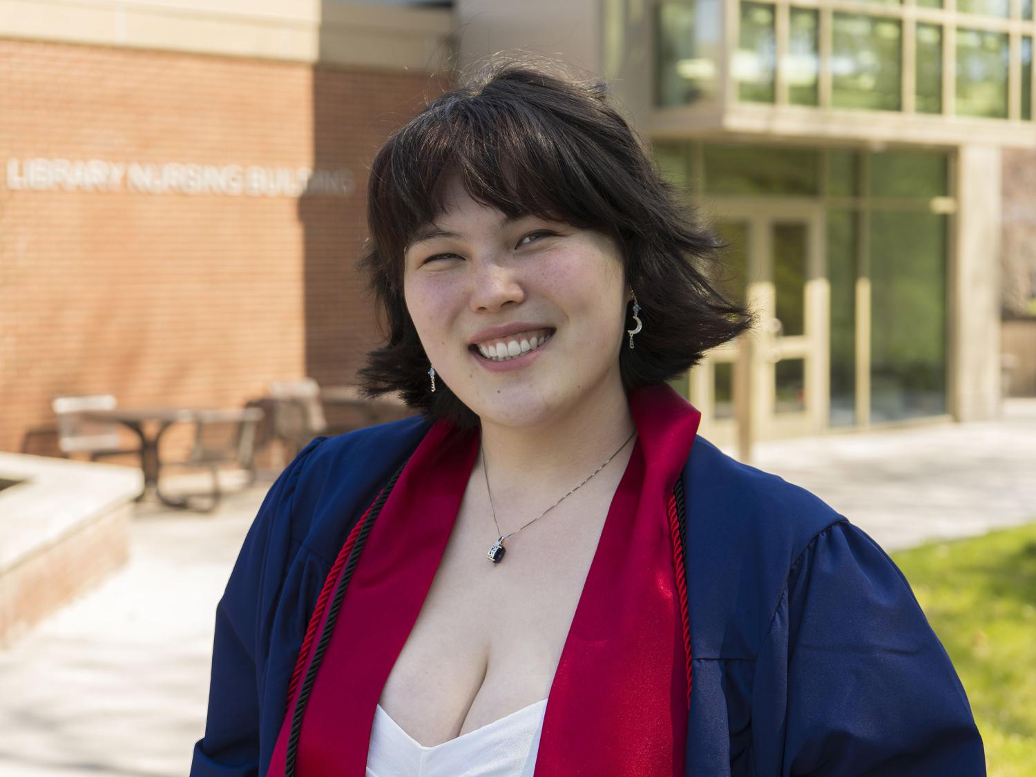 Penn State female graduate smiles for a photo wearing blue commencement reglia. 