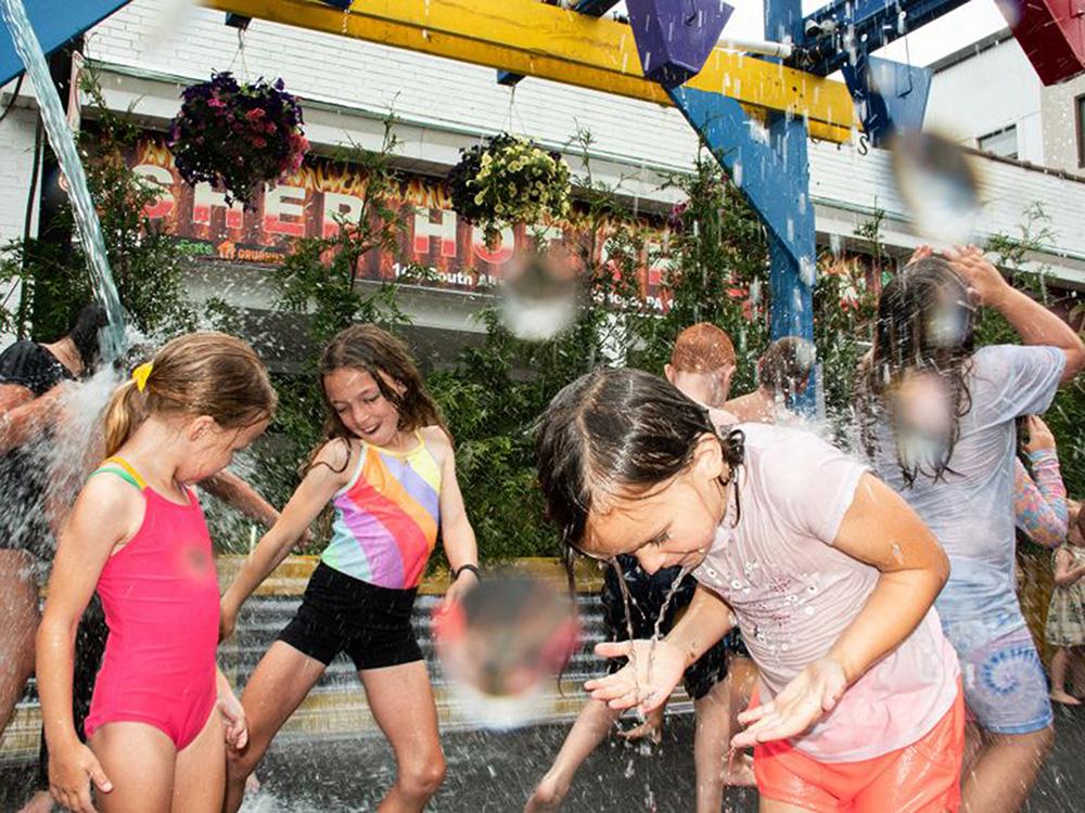 Children react as water pours on them form suspended buckets.