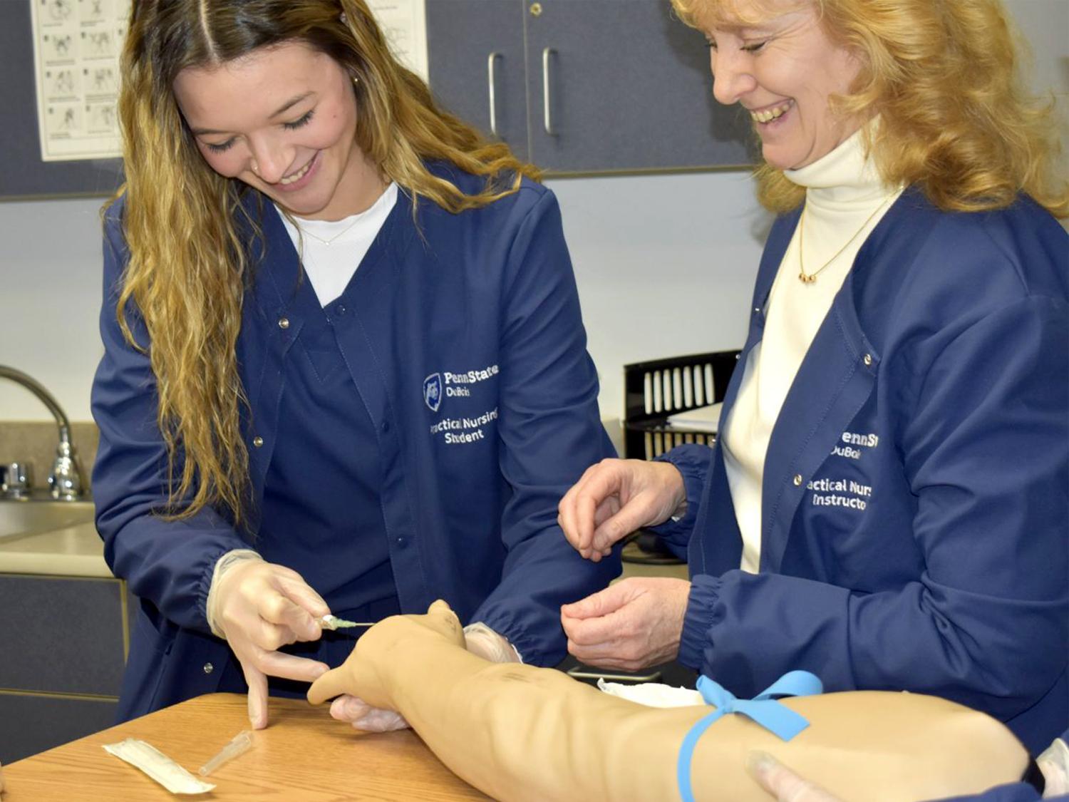 Practical Nursing student Mikayla Grienseisen works through an educational exercise, under the watchful eye of instructor Lisa Dush, RN, MSN, in the Practical Nursing lab at Penn State DuBois.