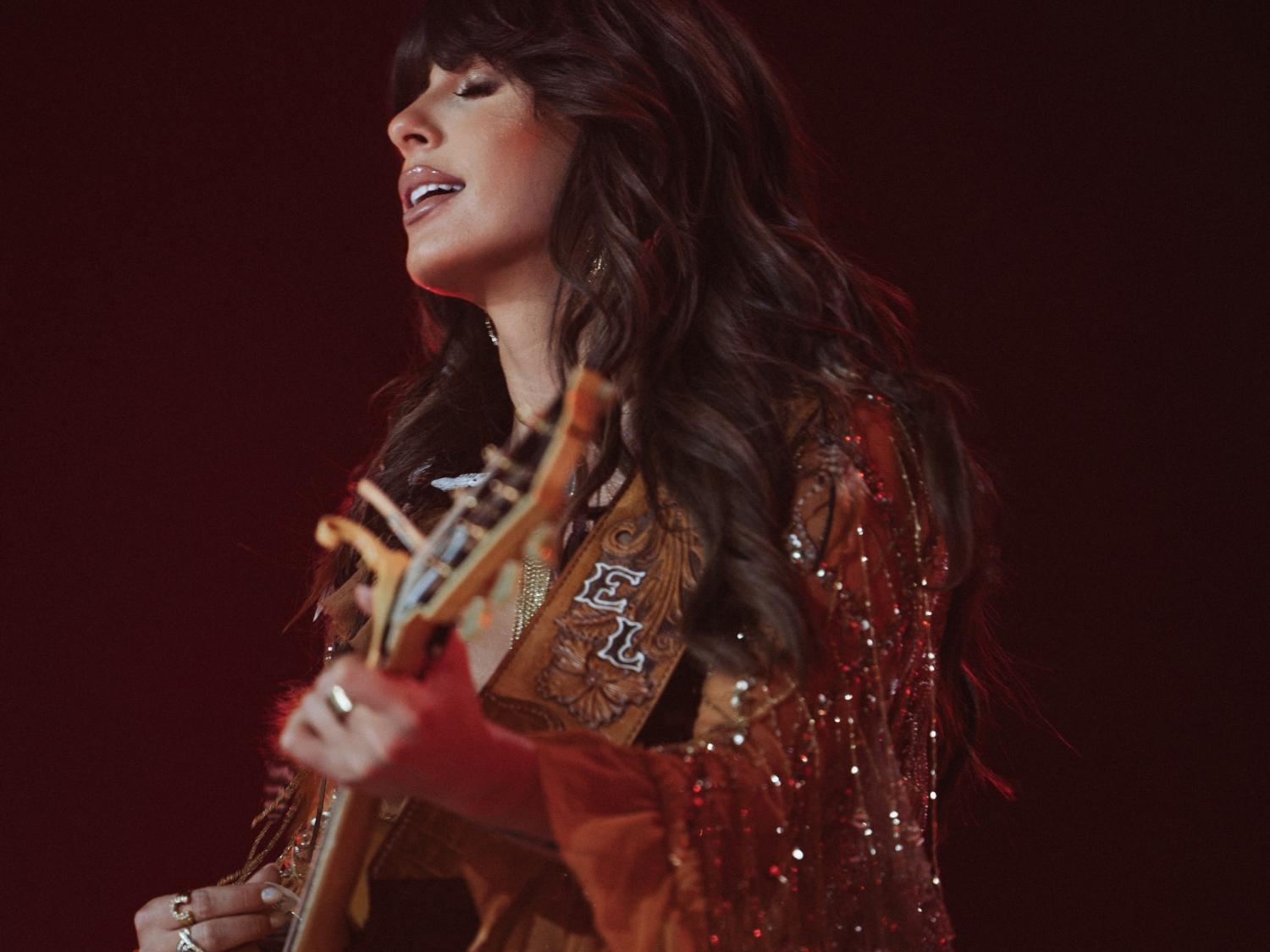 Ella Langley playing guitar and singing with eyes closed.