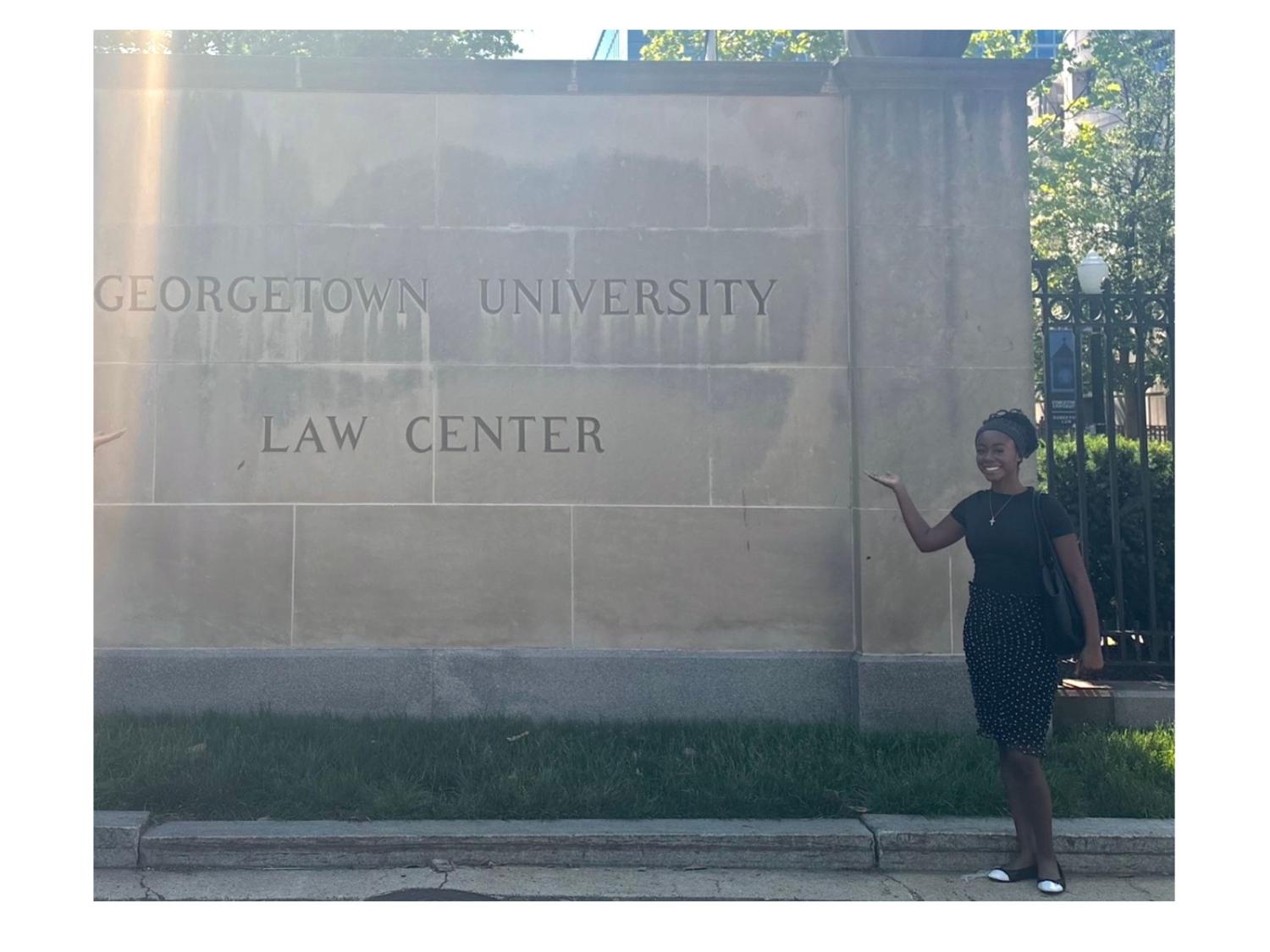 person wearing black dress next to georgetown university law center statue
