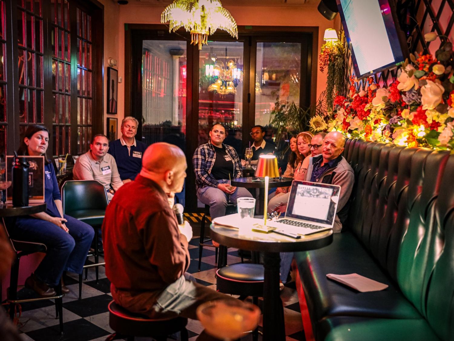Alumni listen intently to a professor lecture in a colorful bar in Philadelphia.