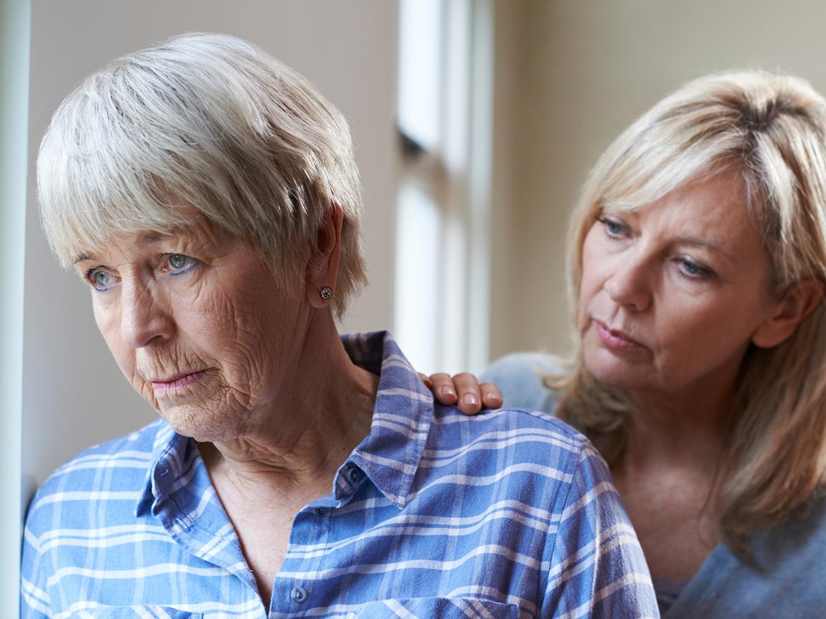 Adult daughter comforts her older mother, who appears sad.