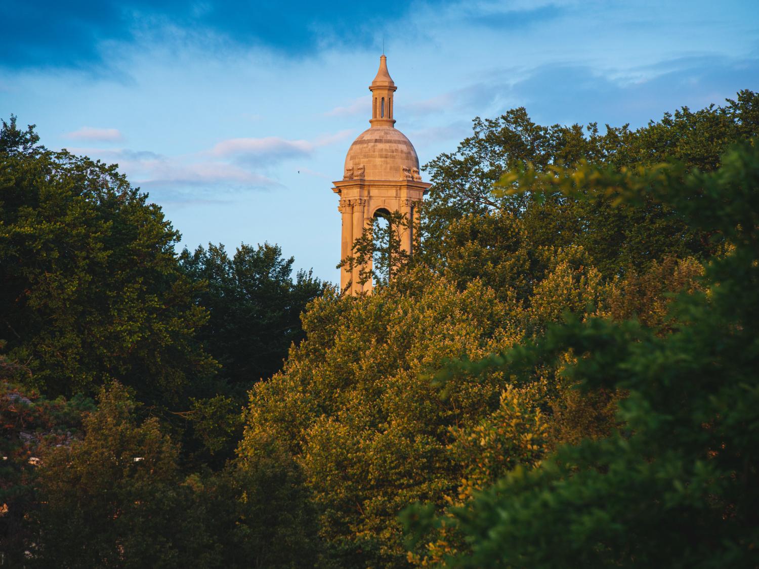 Old Main tower peeking through summer foliage