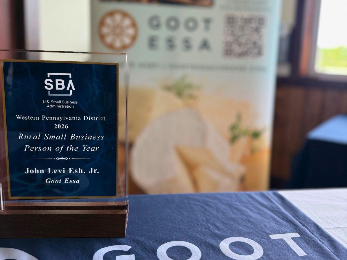 A U.S. Small Business Administration award plaque recognizing the 2026 Western Pennsylvania District Rural Small Business Person of the Year sits on a table beside Goot Essa branded materials, with a blurred promotional display in the background.