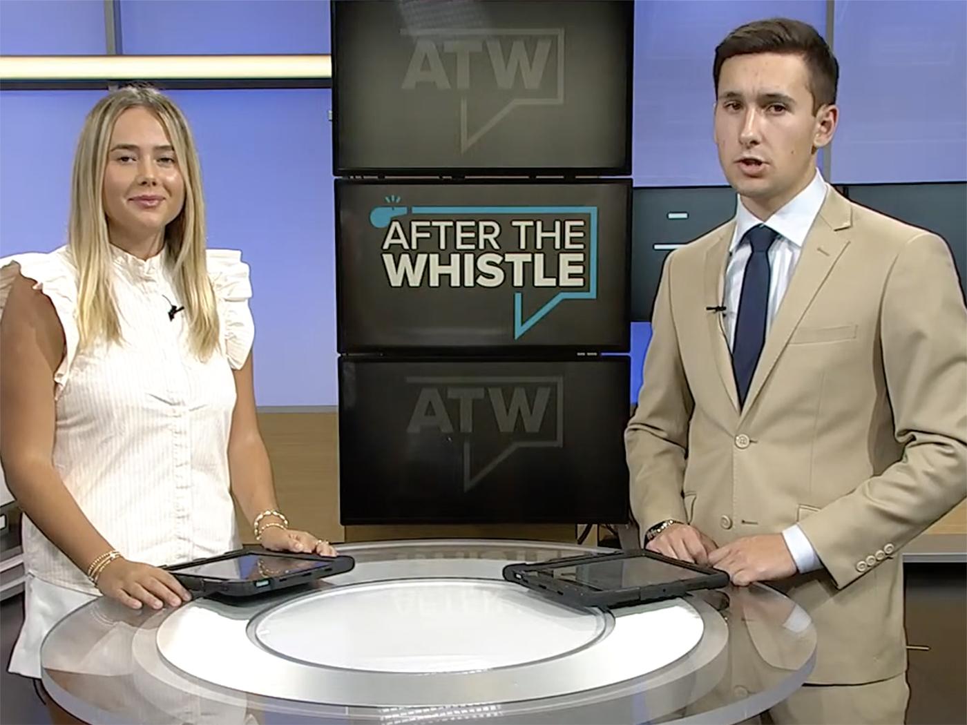 A girl in white and a boy in a light suit stand on a TV set