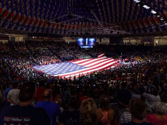 An American flag spread out across a crowded indoor gymnasium