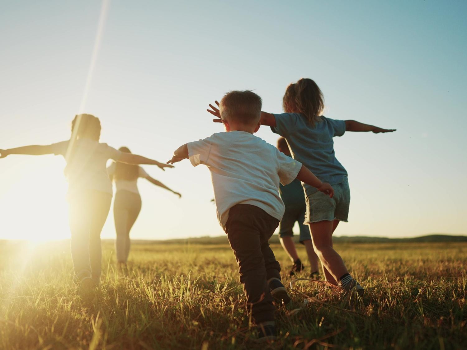 Children running through field during sunset.