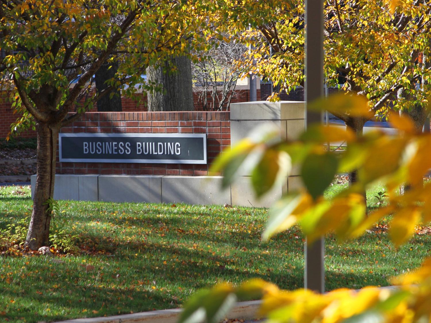 A sign reading Business Building on the Penn State University Park Campus surrounded by leaves and grass