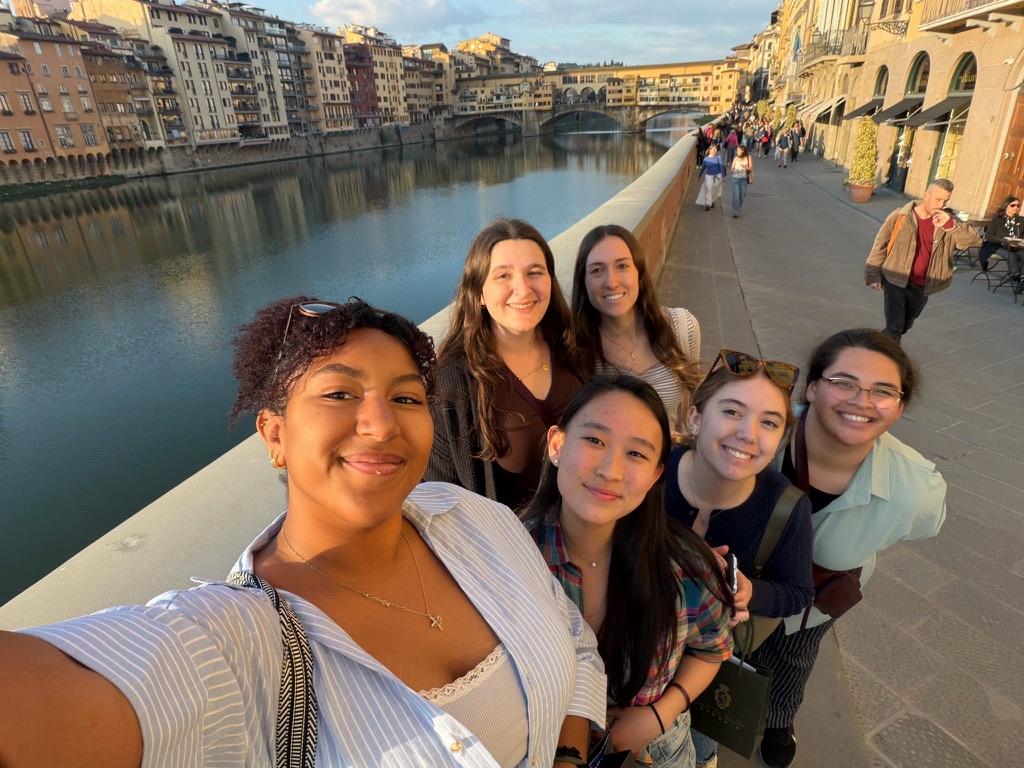 A group of six students, five female and one male, taking a selfie along an Italian riviera