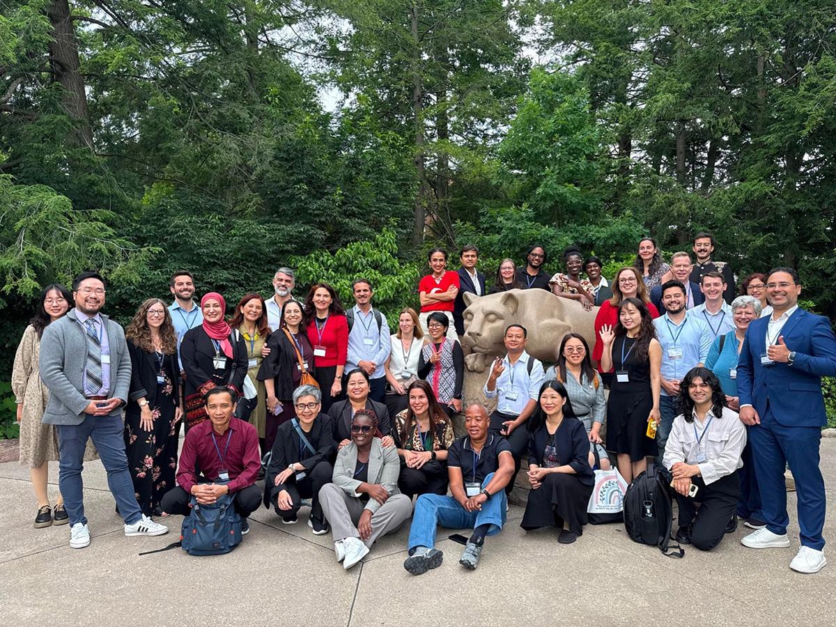 International exchange participants stand and kneel around Penn State Nittany Lion Shrine